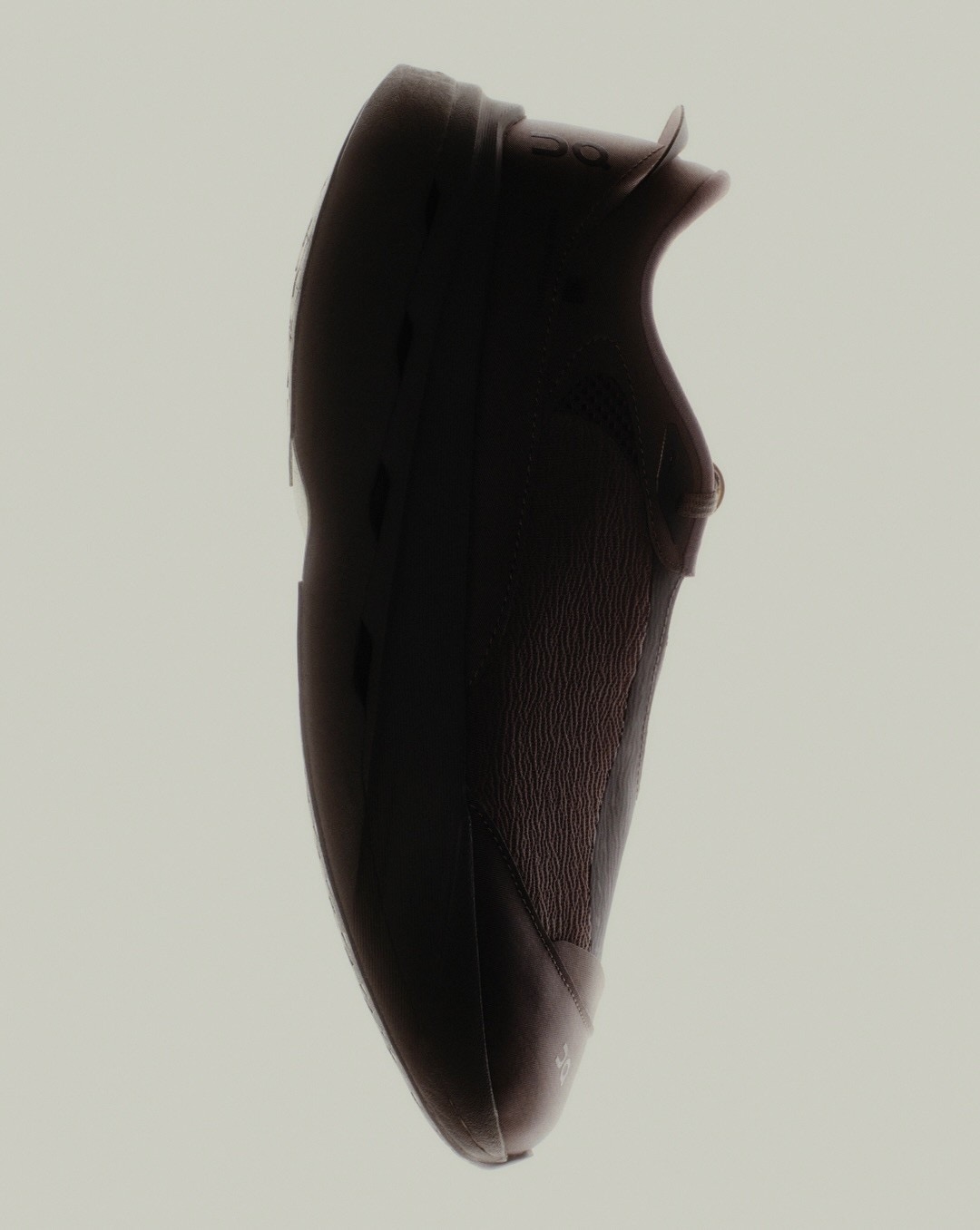 Sleek dark mule shown in three-quarter studio light on stone