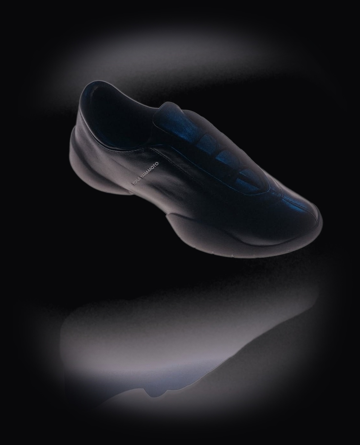Yohji Yamamoto low-profile architectural black trainer viewed in minimalist studio lighting